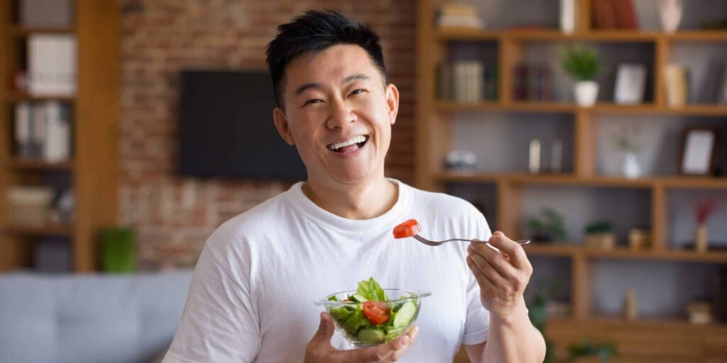 Happy,Asian,Mature,Man,Holding,Fork,And,Bowl,With,Fresh